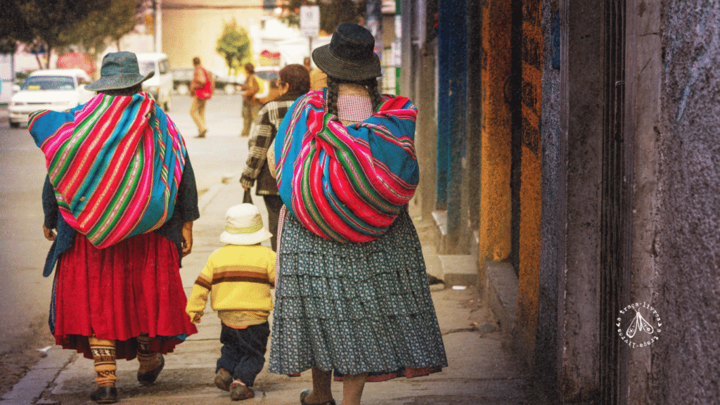 Duas mulheres do povo indígena Aymara e uma criança caminhando de costas, trazendo a identidade andina presente em Terra fresca da sua tumba.